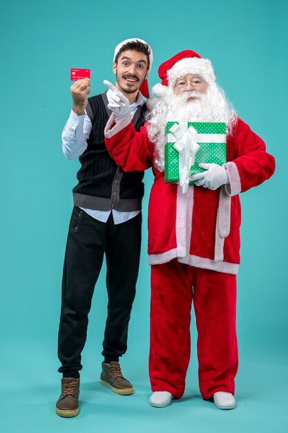 Vista frontal do papai noel segurando um presente com jovem homem