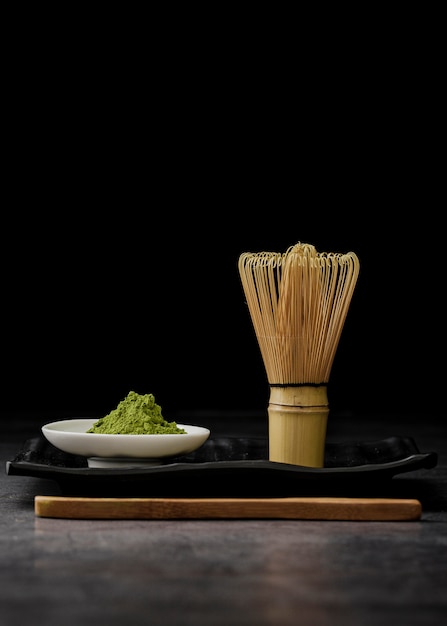 Vista frontal do pó de chá matcha com batedor de bambu