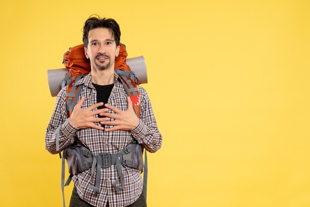 Vista frontal do sexo masculino jovem indo em uma caminhada com uma mochila em um fundo amarelo cor humana viagem campus turístico altura da montanha