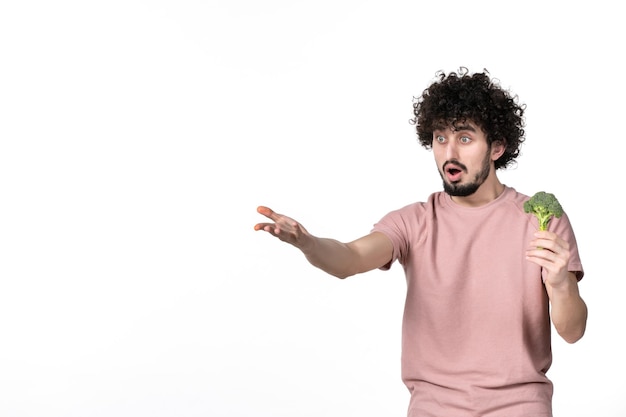 Vista frontal do sexo masculino jovem segurando um pequeno brócolis verde no fundo branco salada corpo saúde horizontal dieta vegetal humana