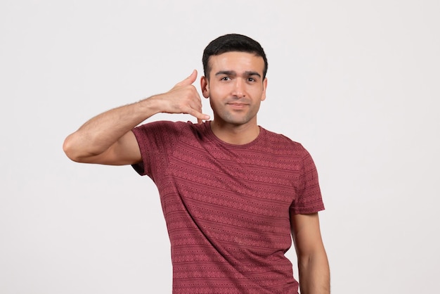 Foto grátis vista frontal do sexo masculino jovem vestindo camiseta e em pé sobre um fundo branco