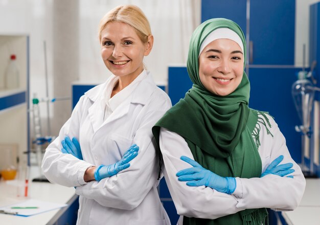 Vista frontal do smiley cientistas femininos no laboratório posando com os braços cruzados