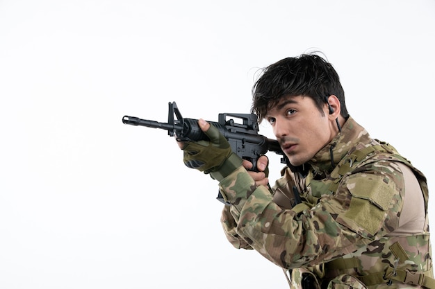 Foto grátis vista frontal do soldado masculino lutando durante a guerra com uma parede branca de metralhadora