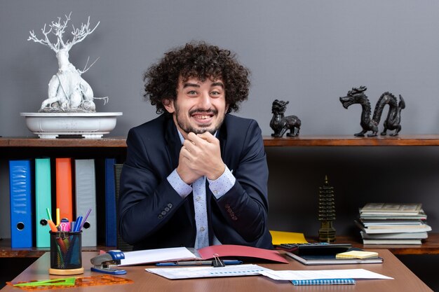 Vista frontal do trabalhador de escritório sorridente, sentado à mesa no escritório