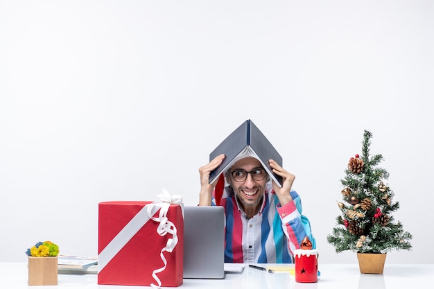 Foto grátis vista frontal do trabalhador masculino sentado em seu local de trabalho segurando um caderno escritório negócios trabalho emoção natal