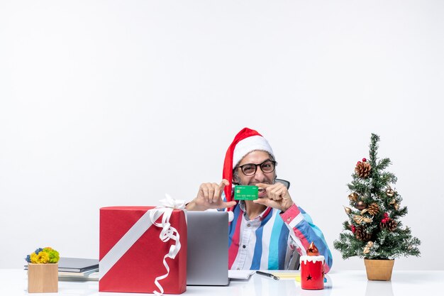 Vista frontal do trabalhador masculino sentado em seu local de trabalho segurando um cartão de banco verde férias emoção Natal escritório dinheiro