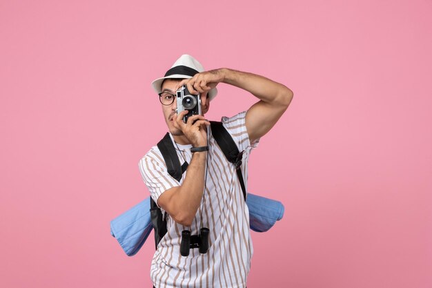 Vista frontal do turista masculino tirando foto com a câmera na cor rosa da emoção do turista