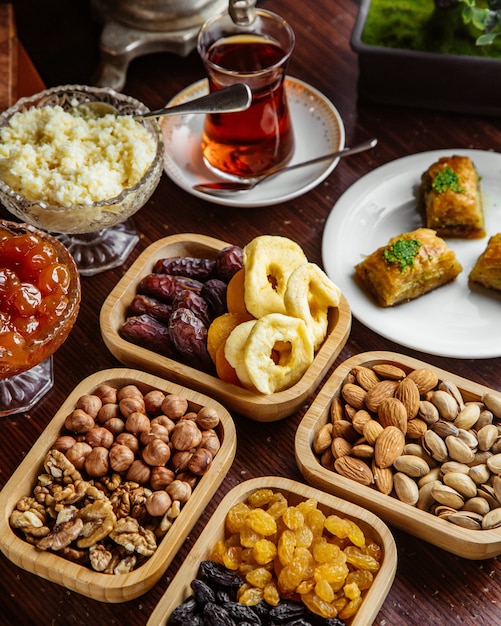 Vista frontal doces conjunto de chá nozes pistache frutas secas baklava com um copo de chá