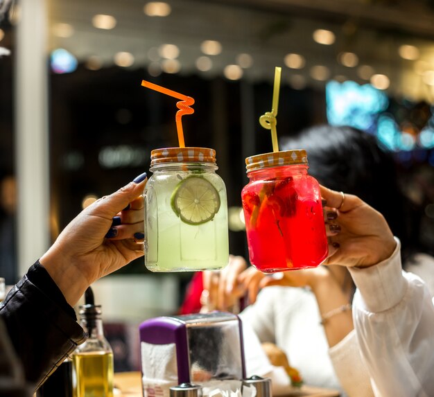 Vista frontal, duas mulheres segurar duas limonada com uma fatia de limão e morangos