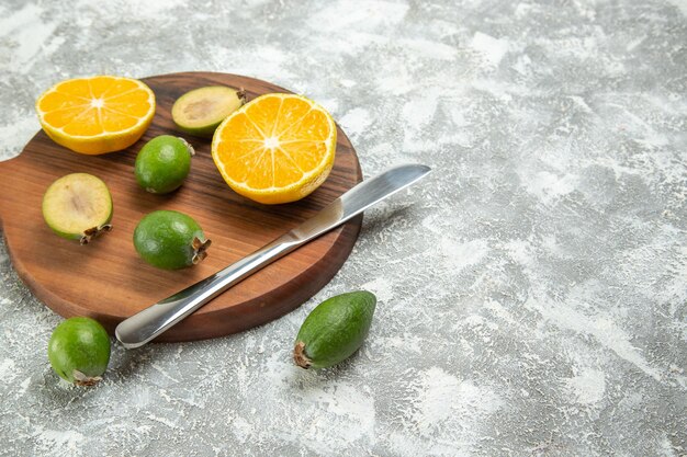 Vista frontal em fatias de laranjas frescas com feijoa no fundo branco frutas maduras exóticas tropicais frescas