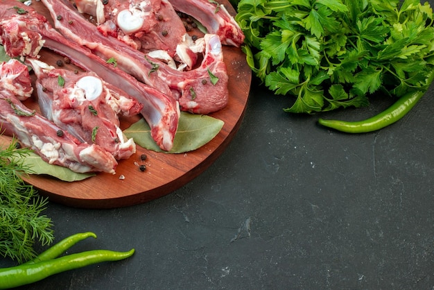 Vista frontal fatias de carne fresca com verdes em fundo escuro carne de açougueiro frango refeição prato comida crua jantar