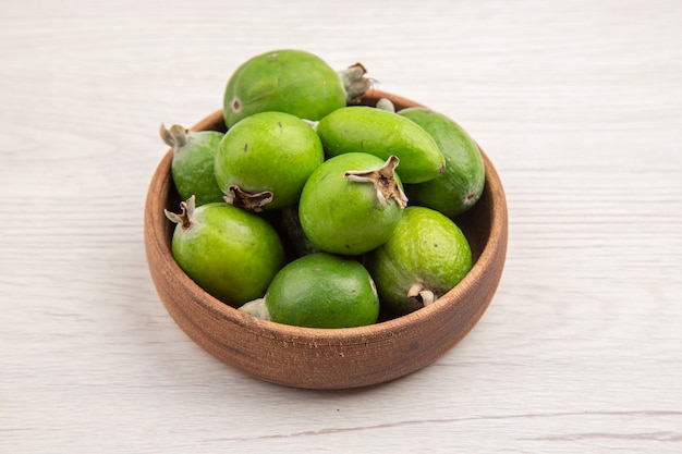 Vista frontal feijoas frescas dentro do prato no fundo branco cor fruta tropical madura dieta exótica