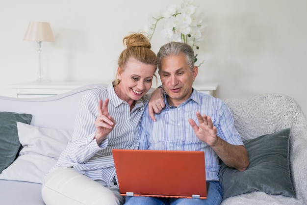 Vista frontal feliz casal sênior com laptop