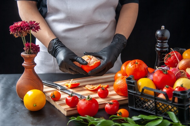 Vista frontal feminina cozinheira limpando tangerinas no escuro cozinhando salada saúde dieta refeição vegetal comida fruta trabalho