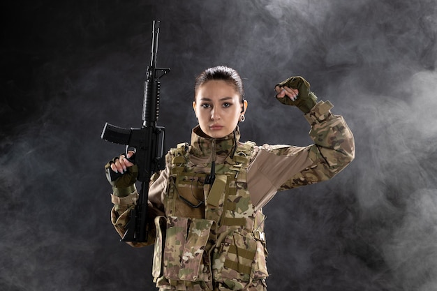 Foto grátis vista frontal feminina soldado de uniforme com rifle na parede preta