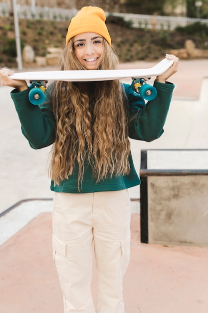 Vista frontal feminino segurando skate