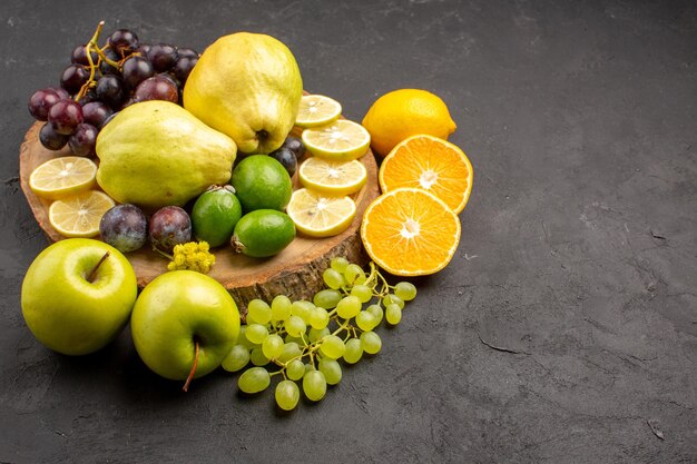 Vista frontal frutas frescas uvas fatias de limão ameixas e marmelos na mesa escura frutas frescas planta madura árvore