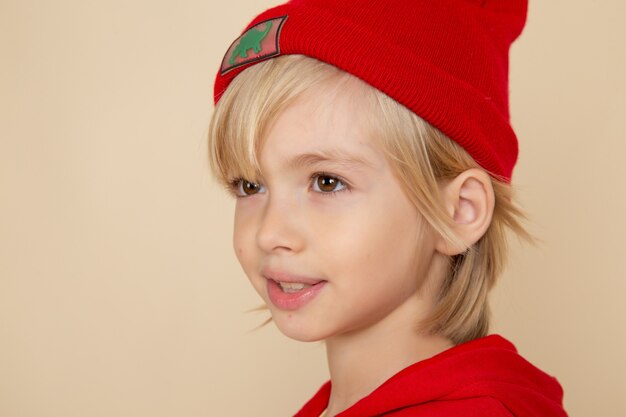 Vista frontal garotinho fofo de camisa vermelha e boné na parede branca