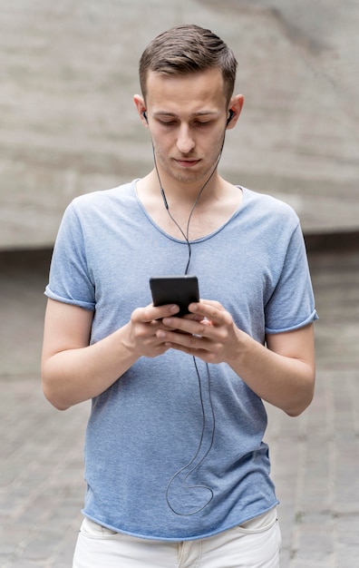 Foto grátis vista frontal homem com fones de ouvido e móveis