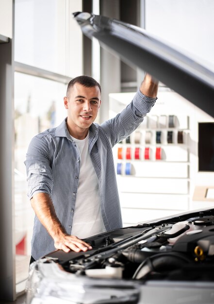 Vista frontal homem feliz verificando um carro