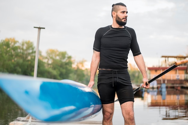 Vista frontal homem segurando canoa e remo