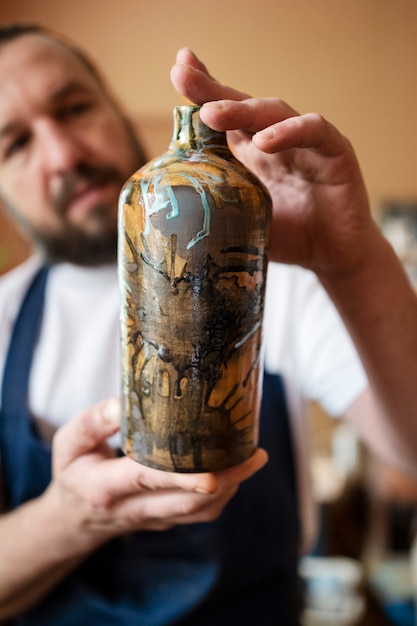 Foto grátis vista frontal homem segurando o vaso pintado