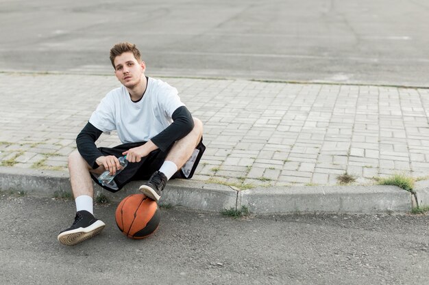 Vista frontal homem sentado com uma bola de basquete