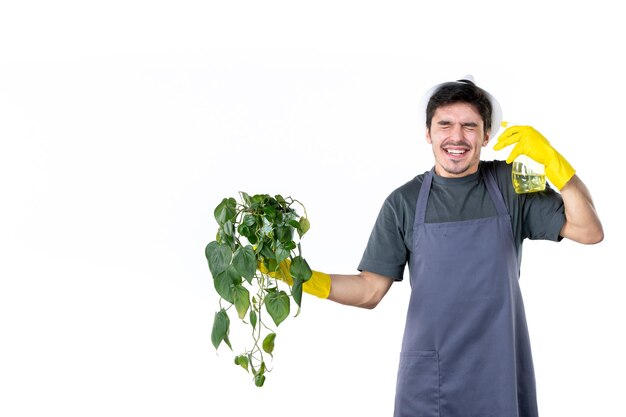 Vista frontal jardineiro masculino segurando planta em vaso e spray em fundo branco árvore de trabalho grama arbusto cor terra trabalho jardim flores