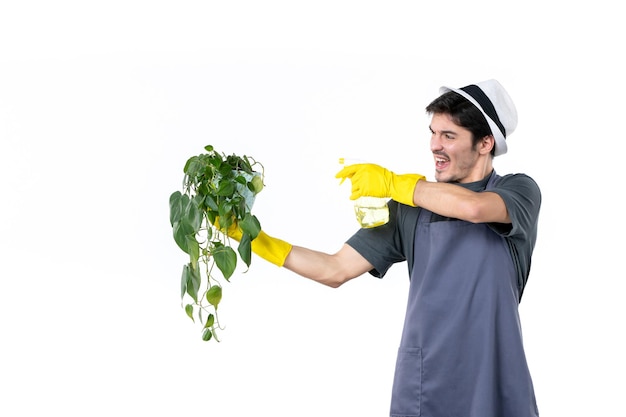 Foto grátis vista frontal jardineiro masculino segurando planta em vaso e spray em fundo branco árvore de trabalho grama chão jardim flor arbusto cor