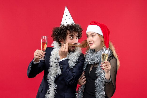 Vista frontal jovem casal comemorando ano novo na festa de amor de Natal na parede vermelha