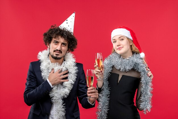 Vista frontal jovem casal comemorando ano novo na festa de parede vermelha amor de natal