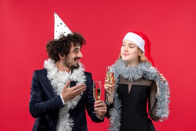 Vista frontal jovem casal comemorando ano novo na festa de parede vermelha amor de natal