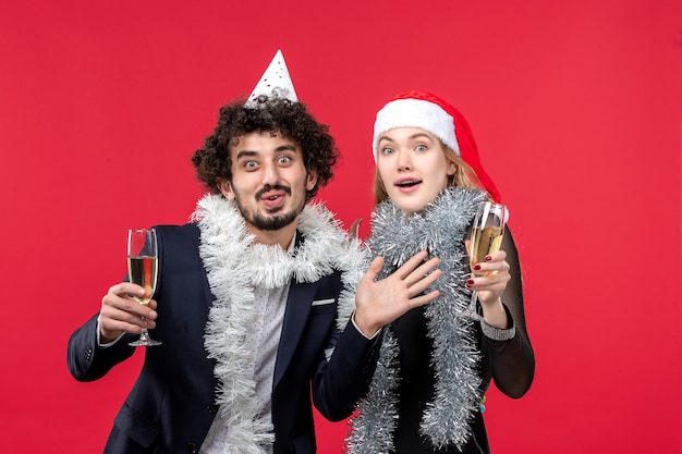 Vista frontal jovem casal comemorando ano novo na parede vermelha feriados Natal amor