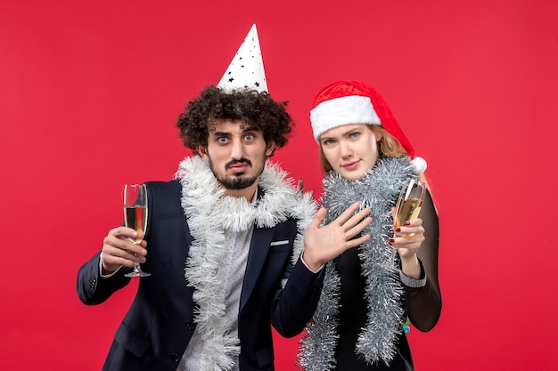 Vista frontal jovem casal comemorando ano novo na parede vermelha férias natal cor amor