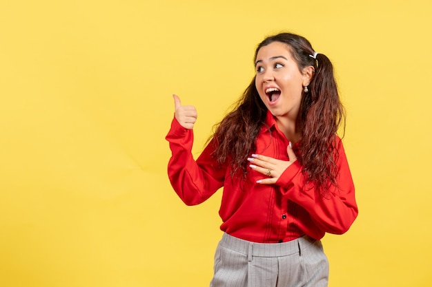 Vista frontal jovem com blusa vermelha com expressão animada em fundo amarelo claro feminino criança criança menina juventude emoção