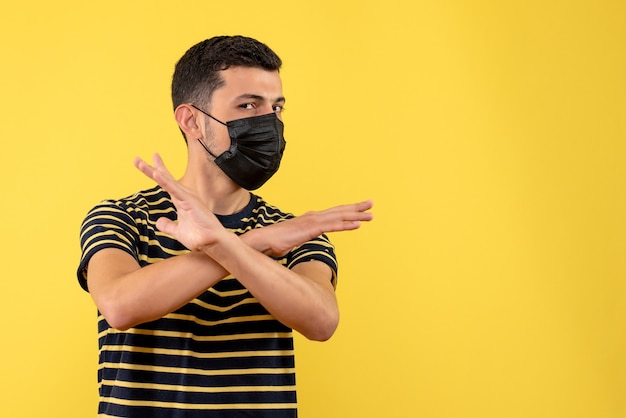 Foto grátis vista frontal jovem com camiseta listrada em preto e branco, cruzando as mãos no fundo amarelo