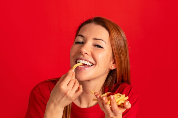 Foto grátis vista frontal jovem comendo batatas fritas