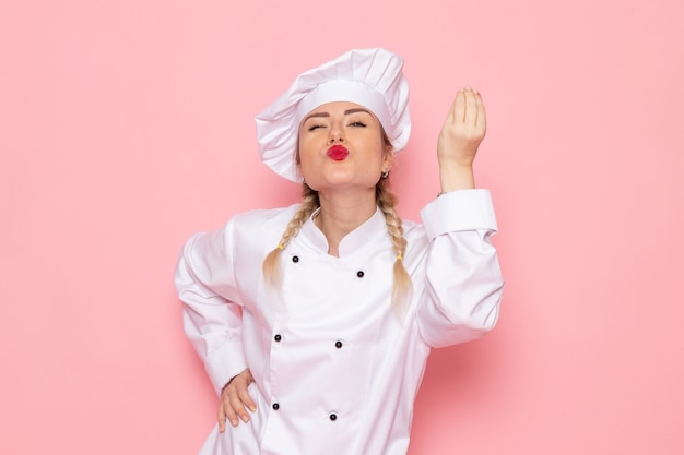 Foto grátis vista frontal jovem cozinheira em terno branco cozinheiro posando e mostrando sinal saboroso no espaço rosa.