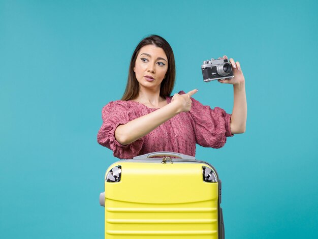 Vista frontal jovem de férias segurando uma câmera fotográfica em uma viagem de fundo azul viagem marítima mulher férias no exterior