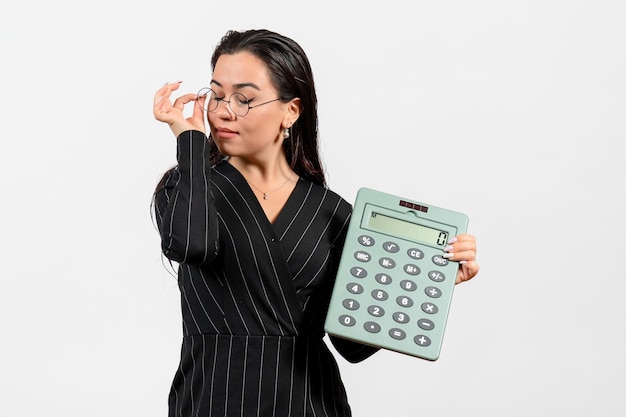 Foto grátis vista frontal jovem de terno escuro segurando uma calculadora grande na mesa branca.