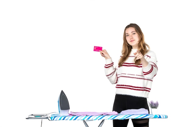 Vista frontal, jovem dona de casa segurando um cartão de banco rosa sobre fundo branco casa trabalho doméstico lavanderia roupa mulher dinheiro limpeza emoção