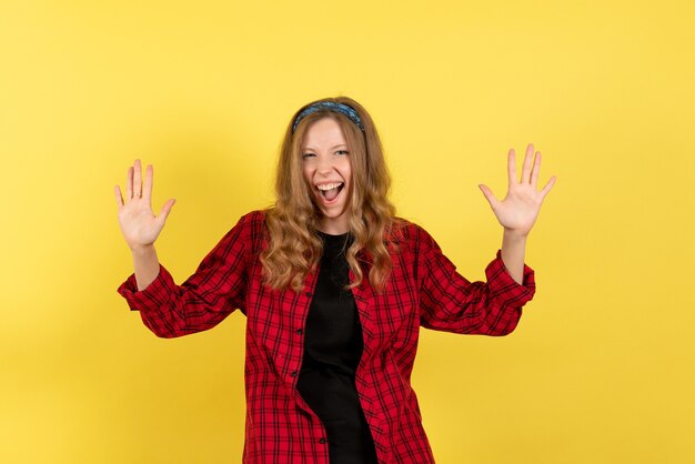 Vista frontal jovem feminina em camisa quadriculada vermelha em pé e gritando na cor de fundo amarelo mulher modelo humana garota