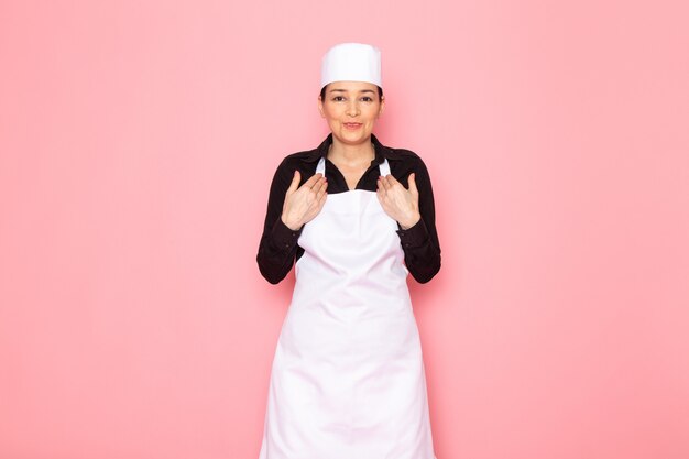 Vista frontal, jovem, femininas, cozinheiro, em, camisa preta, cozinheiro branco, capa, boné branco, posar, sorrindo, falando