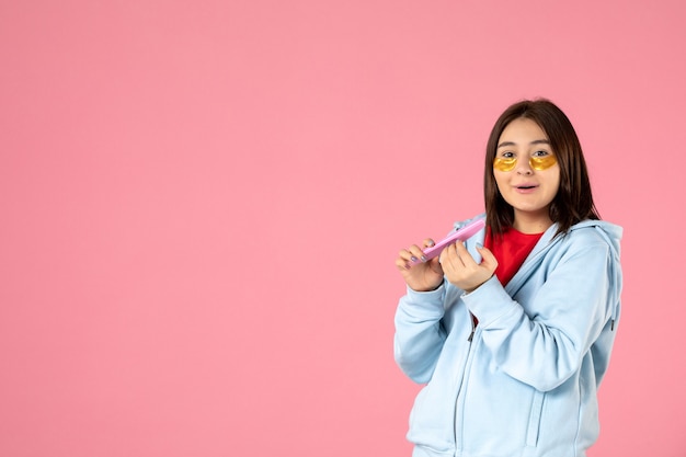 vista frontal jovem, linda mulher, com tapa-olho fazendo as unhas em fundo rosa