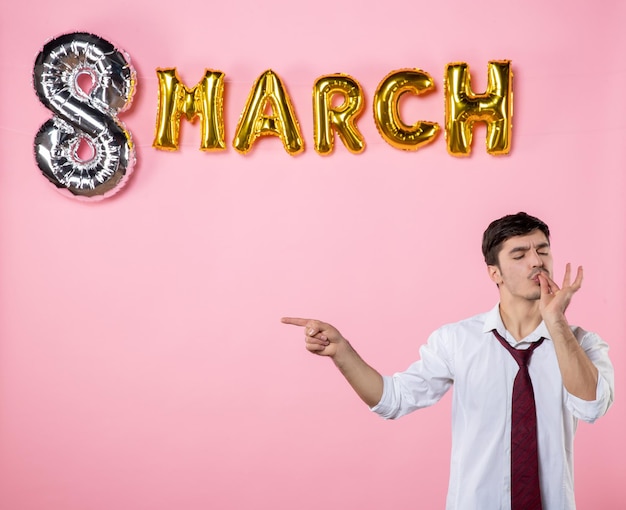 Vista frontal jovem macho com decoração de marcha em fundo rosa presente casamento de festa de igualdade de cores do dia das mulheres femininas