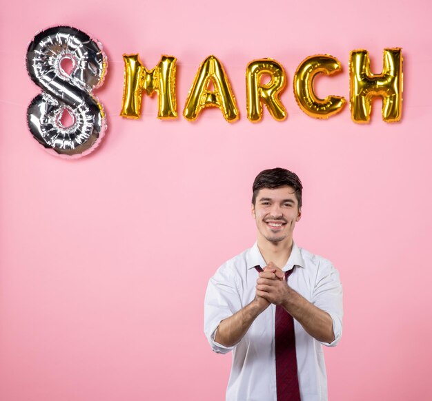 Vista frontal jovem macho com decoração de marcha na cor de fundo rosa casamento feminino dia das mulheres homem marido igualdade presente