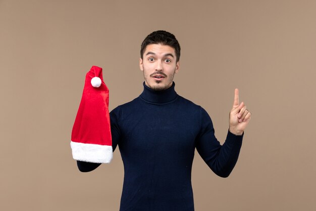 Vista frontal jovem masculino brincando com tampa vermelha na mesa marrom Natal emoção feriado