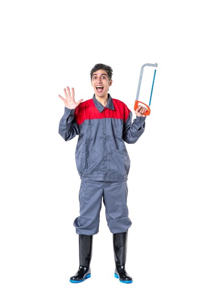 Vista frontal jovem masculino de uniforme com serra no fundo branco faca de trabalho fotos arquitetura edifício trabalho duro corte