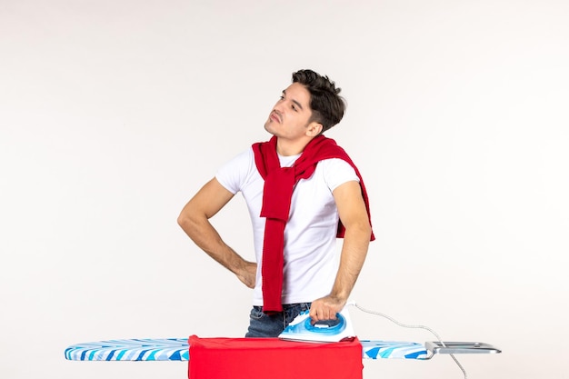 Foto grátis vista frontal jovem masculino segurando ferro no fundo branco trabalho homem trabalho doméstico cor limpa emoção casa