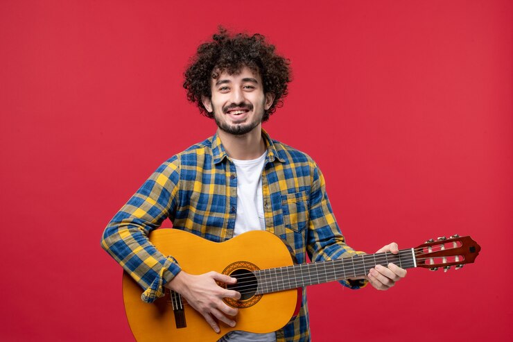 Foto grátis vista frontal jovem masculino tocando guitarra na parede vermelha banda de cores vivas aplausos música tocar músico